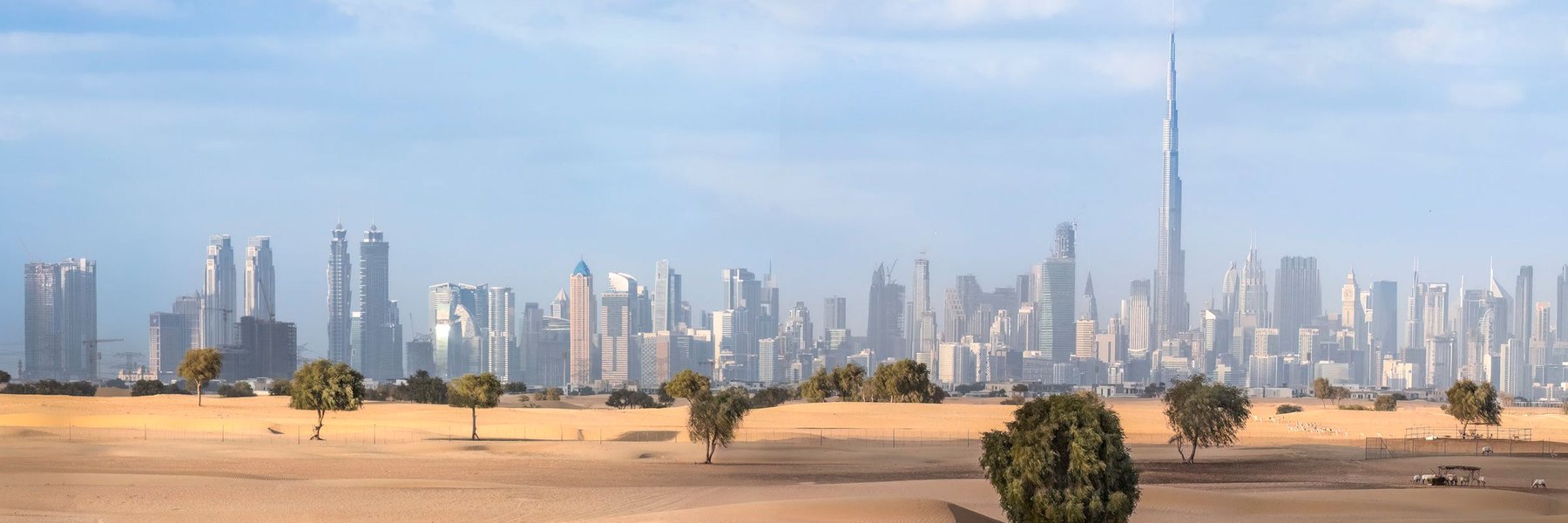 A desert city skyline rising behind open sand.