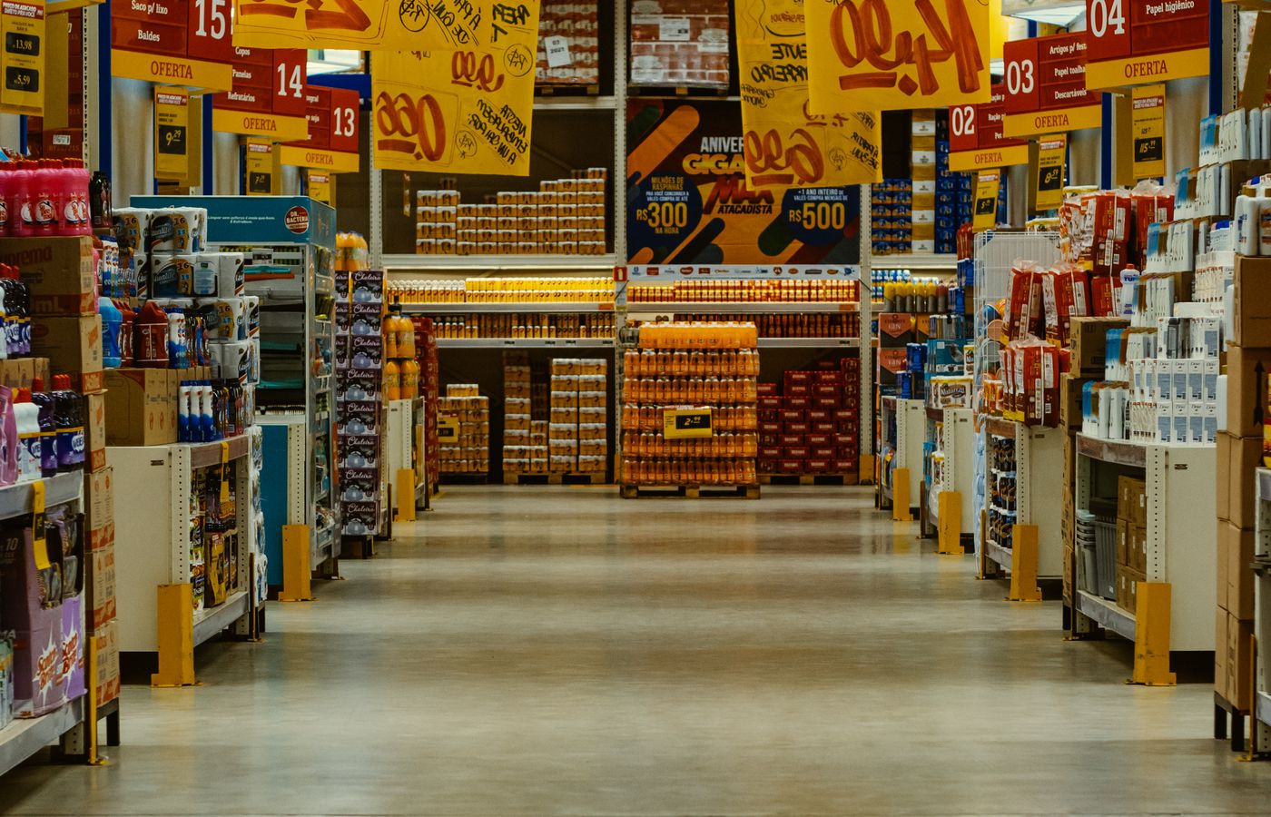 A wholesale supermarket aisle hung with printed price offers.