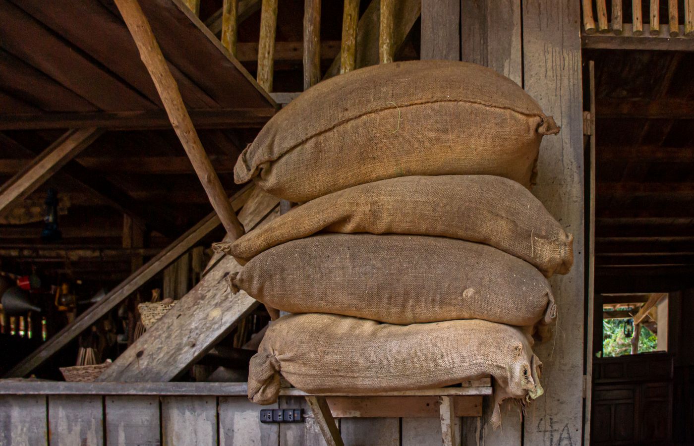 Sacks of grain stacked in a wooden barn.